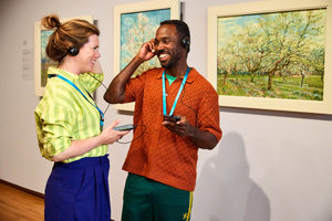 Two visitors at the Van Gogh Museum smile at each other, holding their audio guides. Photo: Suzanne Karsters