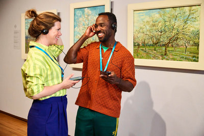 Two visitors at the Van Gogh Museum smile at each other, holding their audio guides. Photo: Suzanne Karsters