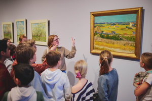 Tijdens een rondleiding in het Van Gogh Museum krijgt een groepje leerlingen uitleg bij het schilderij De oogst van Vincent van Gogh. Foto: David Stegenga