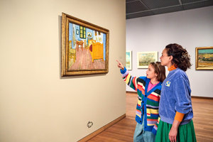 Een meisje wijst naar het schilderij De slaapkamer van Vincent van Gogh in het Van Gogh Museum. Haar moeder staat naast haar en kijkt mee. Foto Suzanne Karsters