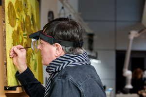 Senior Restaurator René Boitelle restaureert het schilderij Zonnebloemen van Vincent van Gogh. Foto: Maartje Strijbis