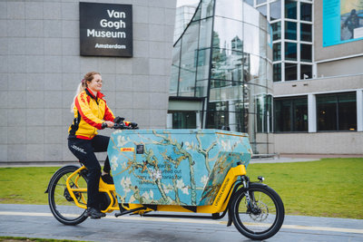 DHL pakketbezorger met haar bakfiets op het Museumplein voor het Van Gogh Museum. Foto: Jelle draper