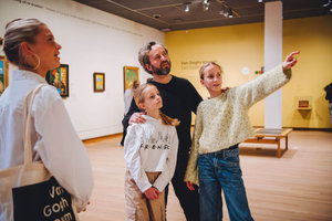 Een vader en zijn twee dochters doen een familierondleiding in het Van Gogh Museum. De oudste dochter wijst naar een schilderij buiten beeld. Foto: Jelle Draper