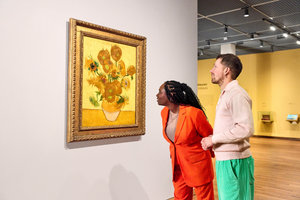 Een bevriend stel kijkt naar het schilderij Zonnebloemen van Vincent van Gogh in het Van Gogh Museum. De vrouw helt wat voorover om het werk nog beter te zien. Foto Suzanne Karsters